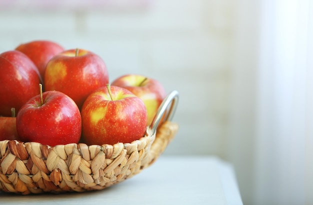 Manzanas rojas maduras en cesta de mimbre en una mesa de cocina