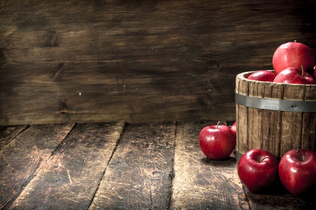 Manzanas rojas maduras en un cubo de madera. Sobre una mesa de madera.