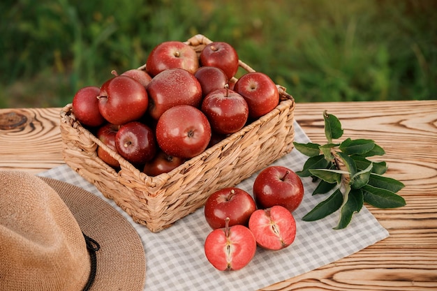 Manzanas rojas maduras frescas en la cesta sobre una mesa de madera con fondo de huerta natural Composición de frutas vegetarianas Concepto de cosecha