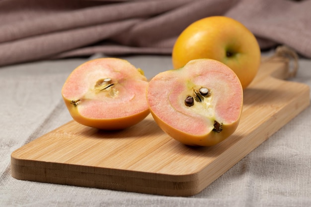 Manzanas rojas maduras frescas cortadas por la mitad en una tabla de cortar de bambú