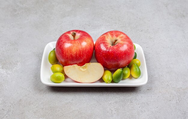 Manzanas rojas maduras con pila de kumquats