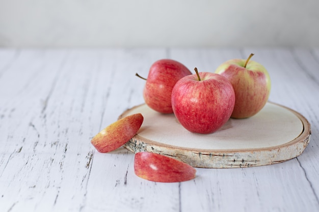 Manzanas rojas maduras sobre un soporte redondo de madera sobre un fondo claro. Aserrado de madera. Nueva cosecha de verano. El concepto de comida sana.