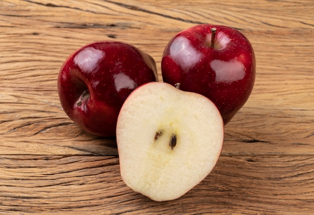 Manzanas rojas y media fruta sobre mesa de madera.