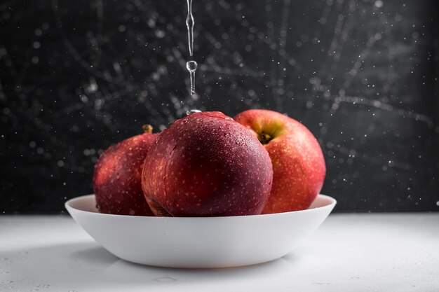 Manzanas rojas en un plato de gotas de agua