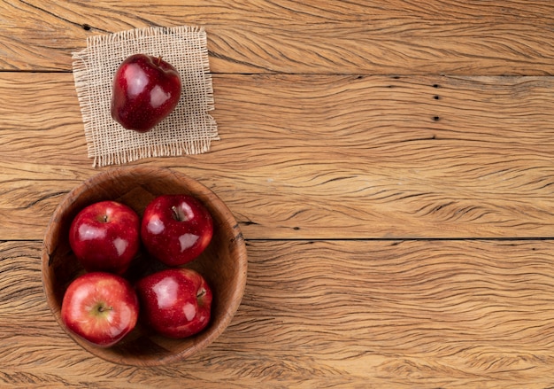 Manzanas rojas en un recipiente sobre la mesa de madera con espacio de copia