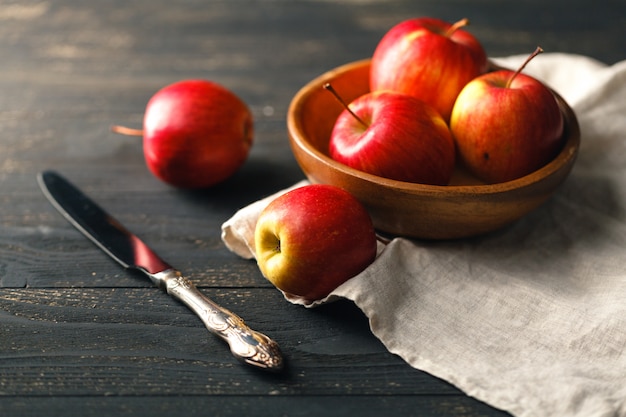 Manzanas rojas en un tazón de madera sobre una superficie oscura