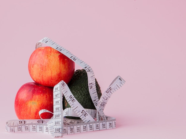 Manzanas rojas con una vara de medir con aguacate en rosa