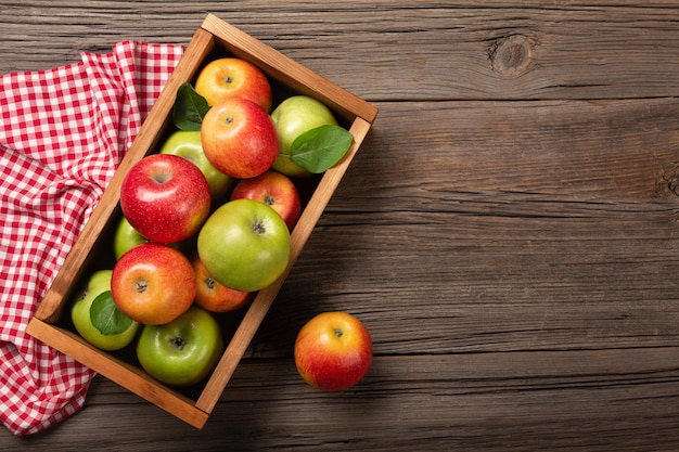 Manzanas rojas y verdes maduras en caja de madera sobre una mesa de madera. Vista superior con espacio para su texto.