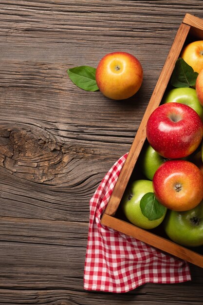 Manzanas rojas y verdes maduras en caja de madera sobre una mesa de madera.