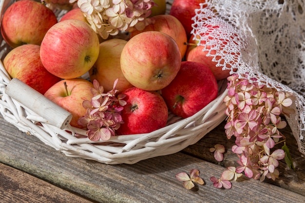 manzanas rosadas en una mesa de madera al sol en una vieja canasta blanca (close up)