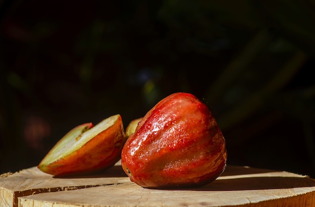 Manzanas rosas (Syzygium jambos) sobre la mesa de madera con fondo oscuro