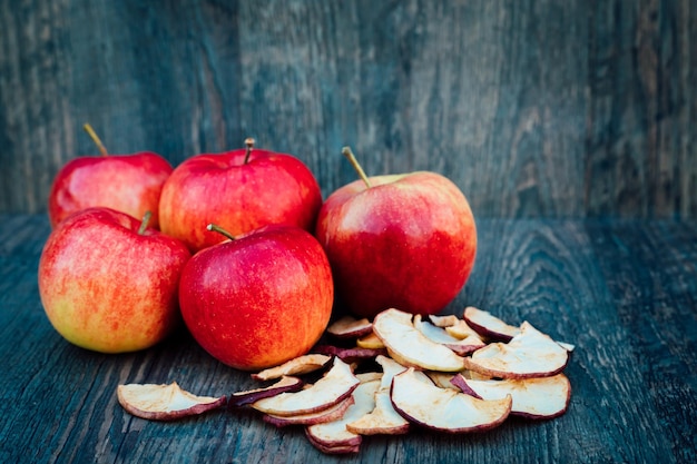 Las manzanas secas y las rosas se encuentran en una mesa de madera oscura.