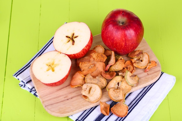 Foto manzanas secas en tabla de cortar sobre fondo de madera de color