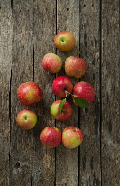 Foto manzanas sobre un fondo de madera antiguo con hojas verdes