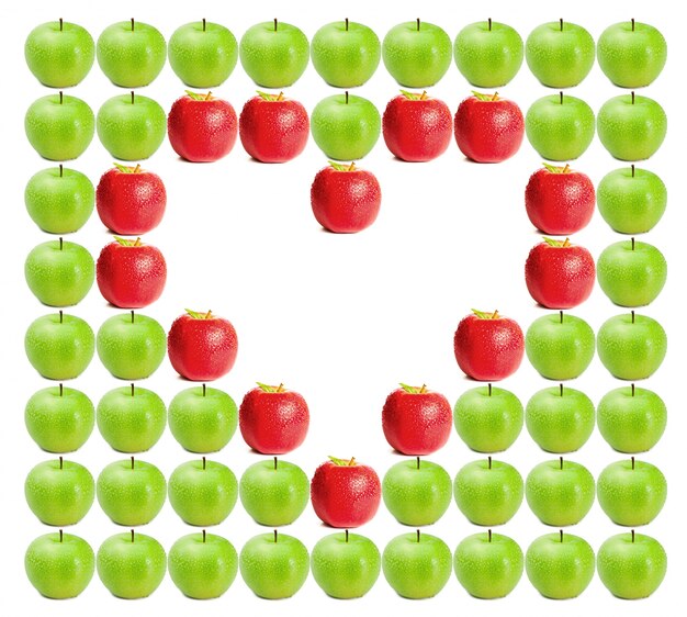 Foto manzanas verde húmedo con manzanas rojas formando un corazón en el medio