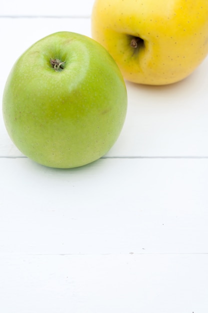Manzanas verdes y amarillas sobre un fondo blanco de madera closeup