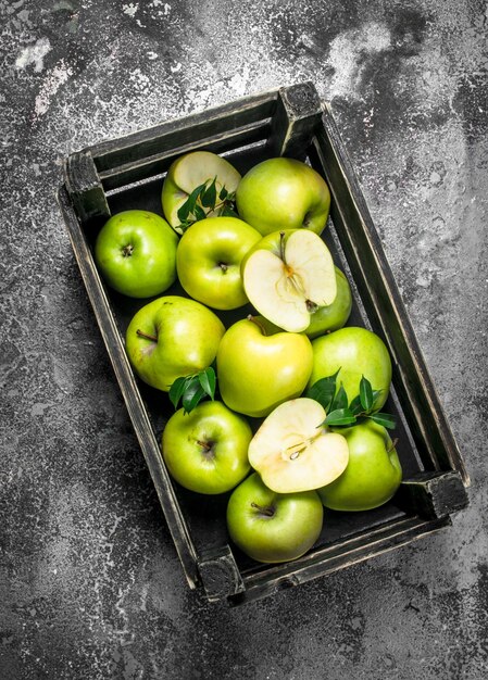 Manzanas verdes en una caja vieja. Sobre una mesa rústica.