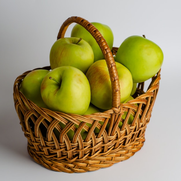 Manzanas verdes en una cesta en blanco. Imagen de la plaza de jardinería