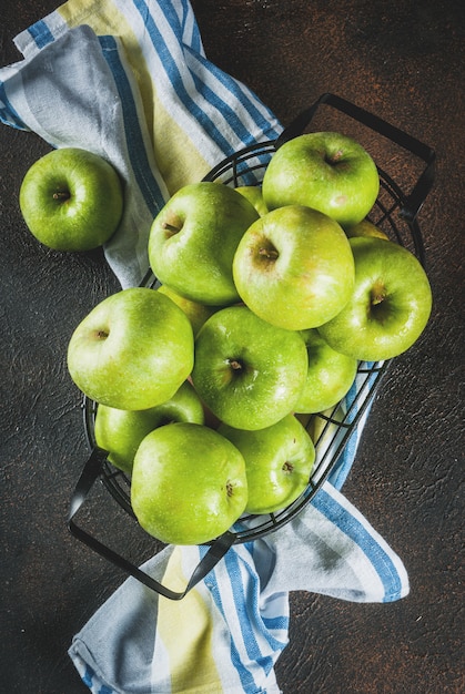 Manzanas verdes crudas frescas orgánicas en cesta de metal negro,