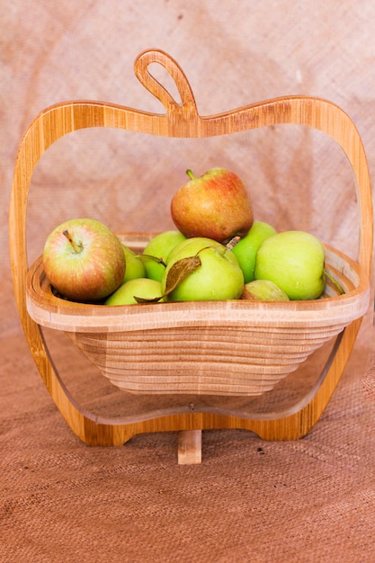 Manzanas verdes y rojas en un florero de madera.