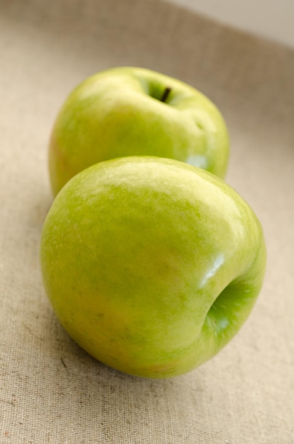 Manzanas verdes sobre lino gris.