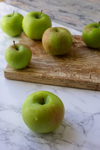 Foto manzanas verdes sobre una tabla de madera para cortar