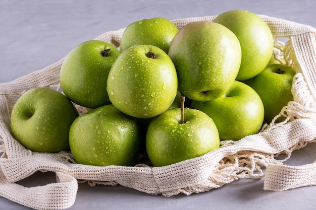 Las manzanas verdes yacen en una bolsa ecológica.