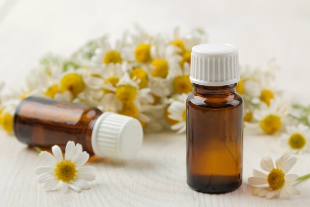 Manzanilla. Pequeñas flores medicinales de manzanilla con aceites aromáticos sobre una mesa de madera blanca. de cerca