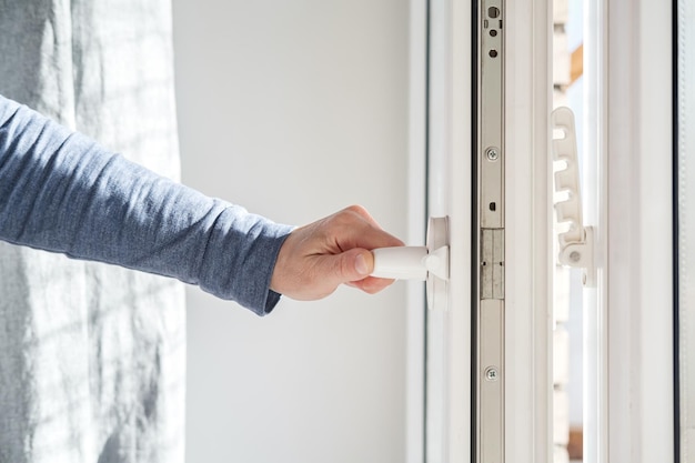 mão abre moderna janela de PVC branco segurando a alça na posição horizontal com um dispositivo de fixação