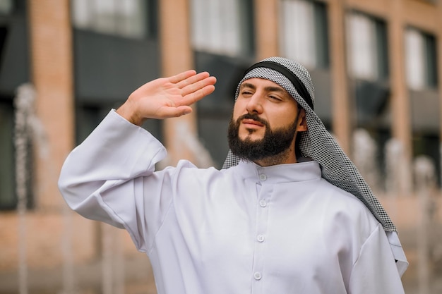 Mão acenando. Um homem com roupas tradicionais árabes acenando com a mão