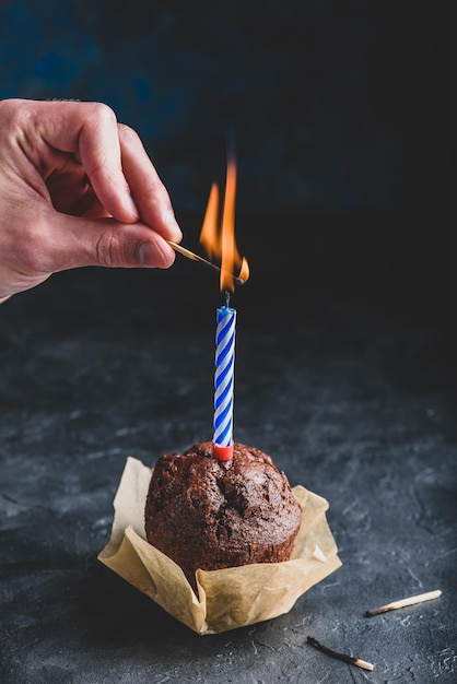 Mão acendendo vela com um fósforo no bolo de chocolate de aniversário
