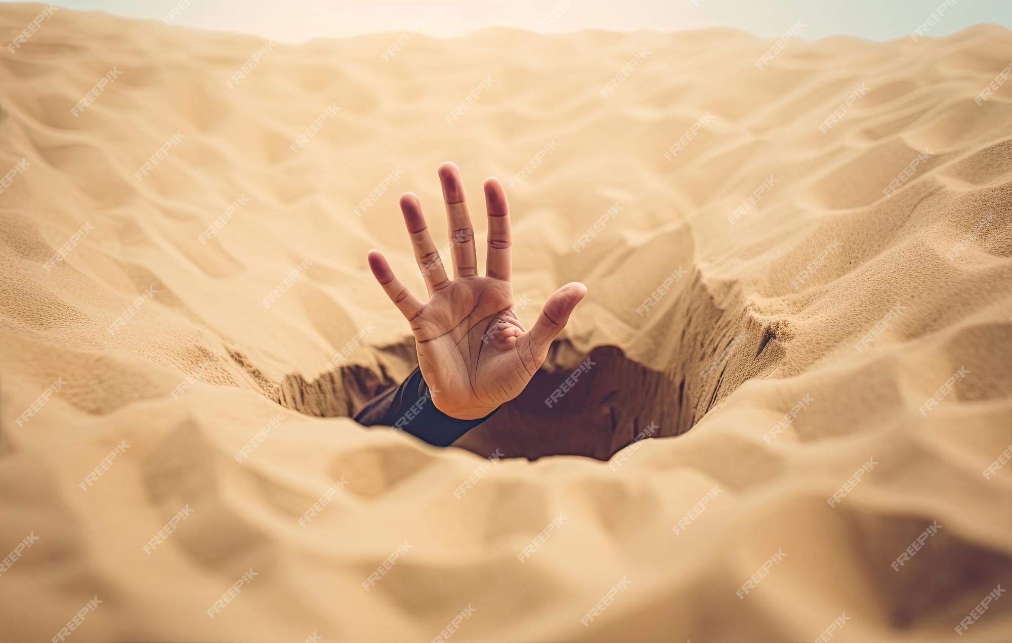 Mão afundando na areia movediça tentando tirar dicas para sobreviver no  deserto enterrado