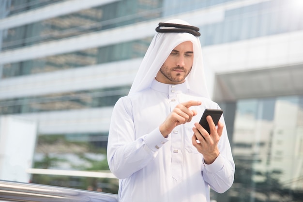 mão árabe do homem de negócios usando o telefone móvel.