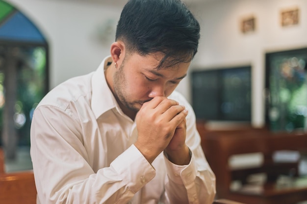 mão asiática com a Bíblia orando, mãos cruzadas em oração em uma Bíblia Sagrada na igreja