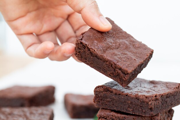 Mão asiática, escolhendo um brownie de Chocolate