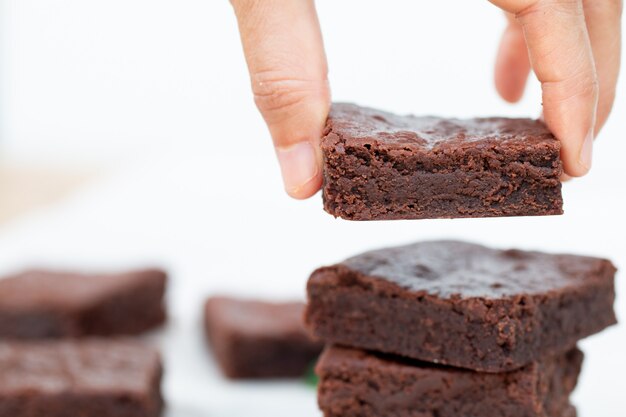 Mão asiática, escolhendo um brownie de Chocolate