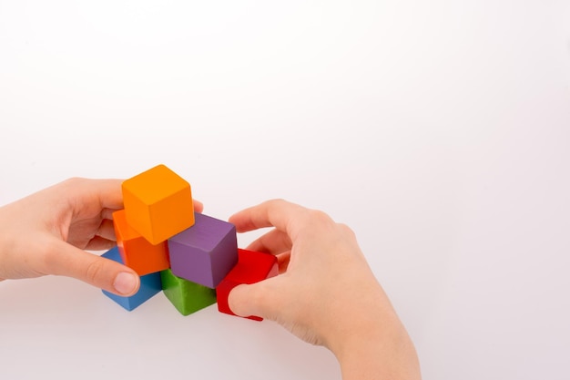 Mão brincando com cubos coloridos em um fundo branco