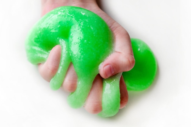 Mão brincando com lodo texturizado com bolhas, esticando a substância pegajosa. Mão de adolescente feminino segurando lodo verde brilhante, apertando-o. Adorável garota esticando o brinquedo de limo para os lados. Brinquedo líquido