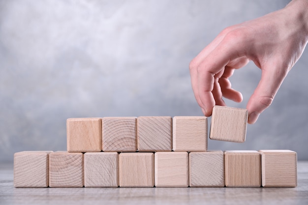 Mão coloca o cubo de madeira em branco