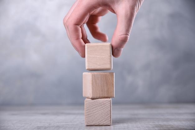 Mão coloca o cubo de madeira em branco