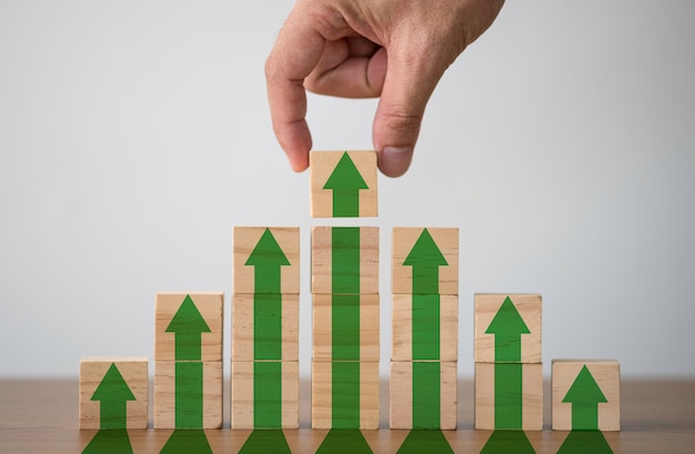 Mão colocando bloco de cubos de madeira que aumentar a tela de impressão ou seta para cima verde.