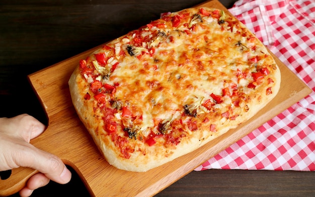 Mão colocando pizza assada fresca Alla Pala Roman estilo pizza em uma pá na mesa