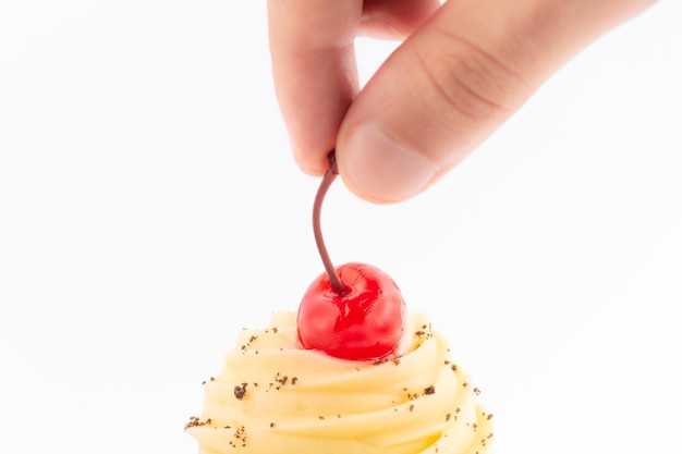 Mão colocando uma cereja em cima do cupcake