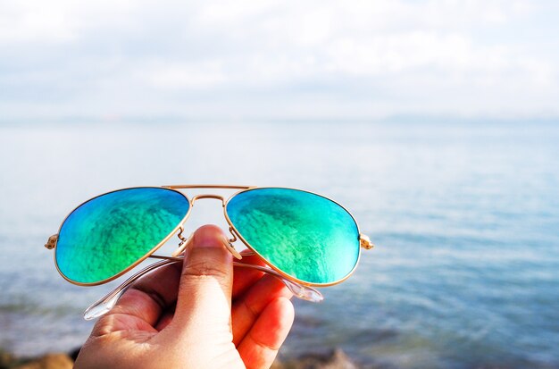 Foto mão, com, azul, óculos de sol, praia