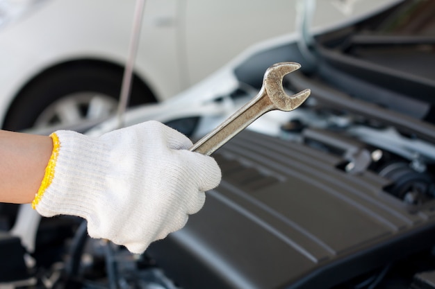 Mão com chave para consertar e verificar o motor do carro