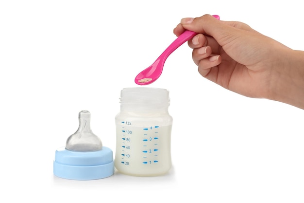 Mão com colher adicionando remédio à fórmula de leite para bebês em fundo branco