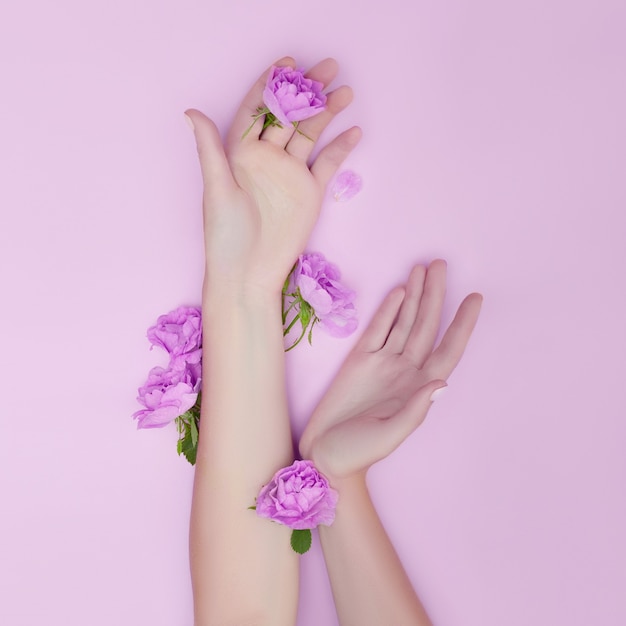 Foto mão com flores cor de rosa e pétalas. cosméticos para cuidados com a pele das mãos