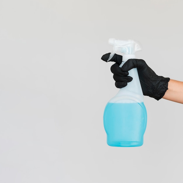Foto mão com luva cirúrgica segurando o frasco de solução de limpeza com espaço de cópia