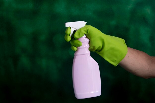Mão com luva protetora segurando embalagens de produtos de limpeza usados para higiene doméstica