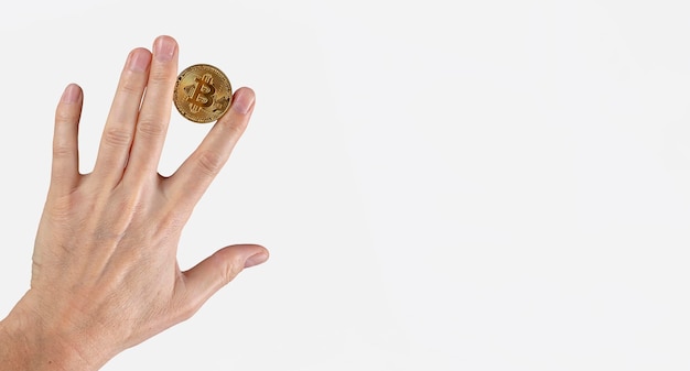 Mão com moeda bitcoin na mão entre os dedos Truques financeiros criptomoeda investindo em banner com espaço de cópia